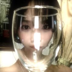 a young woman is holding a wine glass in front of her face