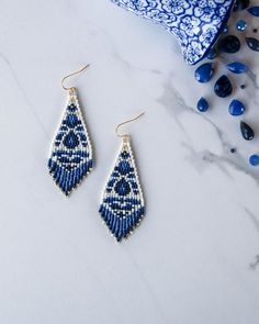 two pairs of blue and white beaded earrings sitting on top of a marble counter