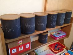 a shelf with chalk writing on it and several bins in front of the shelves