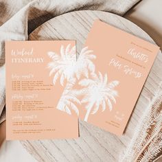 two pink and white palm trees are on top of the wedding stationery, which is laid out on a wooden plate