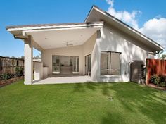 a house that is in the grass with a fence around it and some plants on the lawn