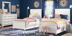 a bedroom with blue walls, white furniture and colorful rugs on the hardwood floor