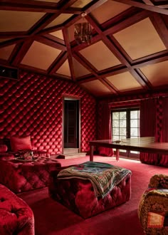 a living room with red walls and couches in the center, tables on either side