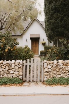 a white house with a stone fence in front of it