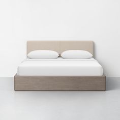 a bed with two pillows on top of it next to a white wall and floor