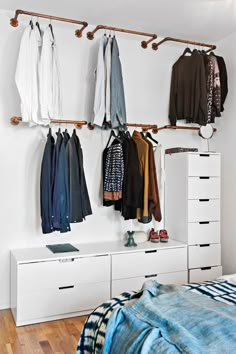 an organized bedroom with clothes hanging on the wall