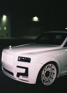 a white car parked in front of a building at night