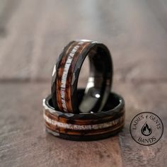 two wedding rings with wood inlays on top of each other, sitting on a table