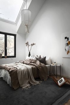 a bed sitting under a skylight in a bedroom next to a table and lamp