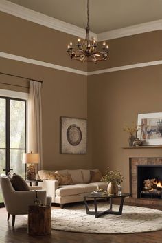 a living room filled with furniture and a fire place under a chandelier in front of a window