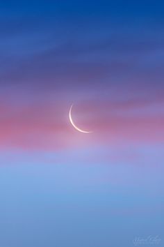 the crescent moon is seen against a pink and blue sky