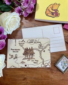 the winnie the pooh postcard is next to some flowers and a card holder