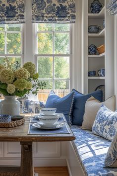 a blue and white living room with flowers in the vase on the window sill