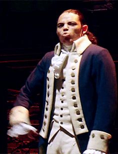 a man dressed in white and blue is standing with his hands on his hips while wearing gloves