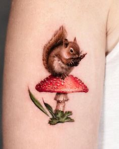 a small squirrel sitting on top of a mushroom with a strawberry in it's mouth