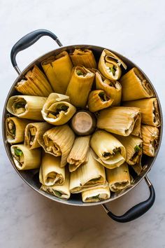 an overhead view of some tamales in a pot on a white counter top with a black handle