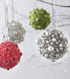 three ornaments hanging from a string on a white surface with snowflakes in the background