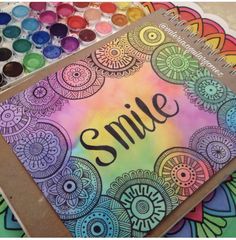 a notebook with the word smile written on it next to some markers and paintbrushes