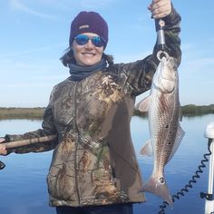 a woman holding a fish while standing on a boat