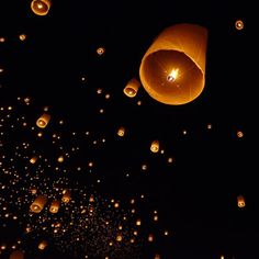 many lit up lanterns floating in the night sky