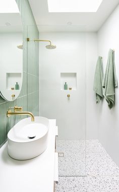 a white sink sitting under a bathroom mirror next to a walk in shower with skylights