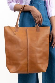 This large, durable leather tote is perfect for bringing along on trips to the farmers market, beach, or picnics. Crafted with high-quality 1.8mm vegetable-tanned Italian leather that is water-resistant and features a zippered shoulder bag design with a front-panel seam, key-hook, and spacious interior pocket. Horween Leather, Key Hooks, Bag Design, Bar Accessories, Knit Tees, Perfect Bag, Large Tote, Sweater And Shorts, The Body Shop