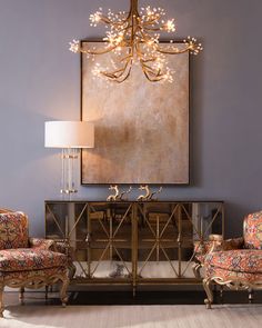 a living room with a chandelier hanging from the ceiling and a painting on the wall