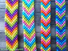 three colorful knitted bracelets sitting on top of a wooden table