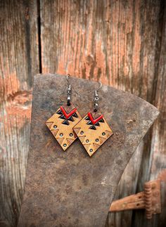 the earrings are made out of wood and have red, black, and white designs on them