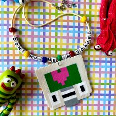 some toys are laying on a colorful table cloth and there is a necklace with an image of a pacman