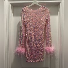 a pink and purple dress hanging on a white door with some feathers attached to it