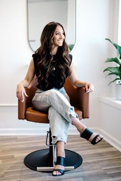 a woman sitting in a brown chair with her legs crossed and one foot on the ground