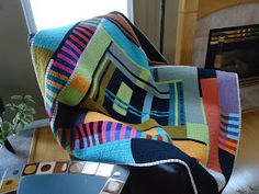 a colorful blanket sitting on top of a chair next to a remote control and fireplace