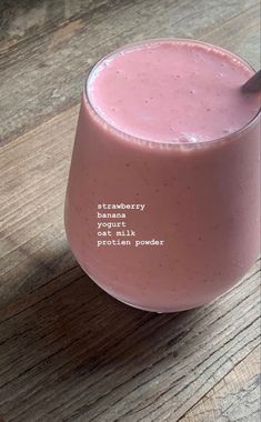 a pink smoothie is sitting on a wooden table