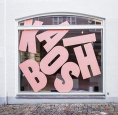 a pink sign that says boosh in front of a window