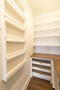 an empty closet with white shelving and wood flooring on the bottom shelf is shown