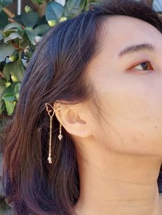 a close up of a person wearing some kind of earring with leaves in the background