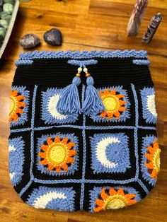 a crocheted bag with sunflowers and tassels on it sitting on a wooden floor