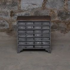 an old chest of drawers sitting in front of a stone wall with no one on it