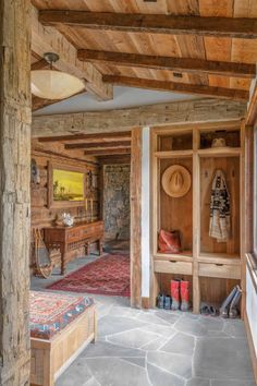 the inside of a rustic cabin with wood paneling and stone flooring, including an entryway