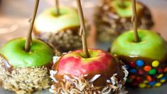 four chocolate covered apples with sprinkles and candy on them are sitting on a plate