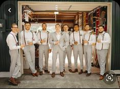 a group of men standing next to each other in front of a garage door wearing ties and suspenders