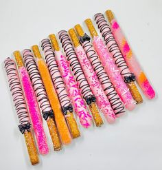 there are many candy sticks that have been decorated with pink and yellow designs on them