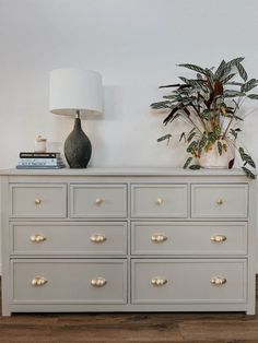 a white dresser with gold drawers and a potted plant sitting on top of it