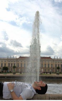 a man laying on the ground next to a water fountain