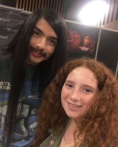 two people standing next to each other with long hair