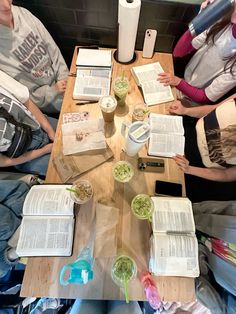 three people sitting at a table with open books