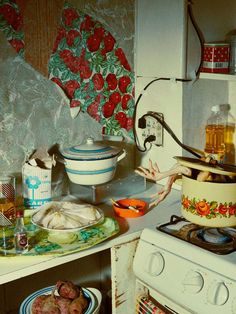 a messy kitchen with food on the stove and dishes in the oven next to it