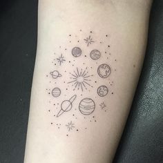 a small tattoo on the arm of a woman with planets and stars around it in black ink