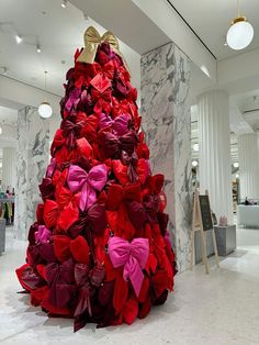 a christmas tree made out of red and pink paper flowers in a room with marble walls